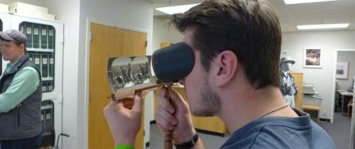 Student examining historical stereographs through a stereoscopic viewer