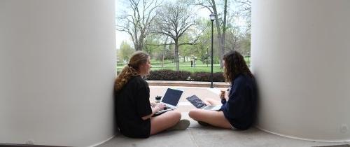 拿着笔记本电脑的学生坐在克朗斯大厅前